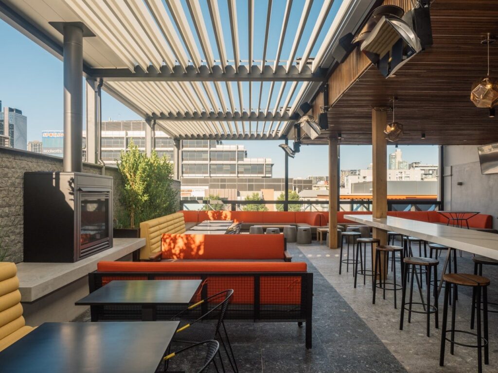 un bar et un restaurant vides sur le toit, avec des chaises longues orange vif et des chauffages au gaz.