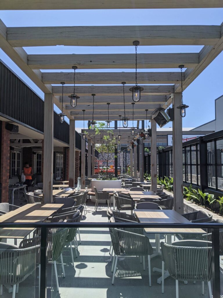 Des sièges à l'extérieur d'un restaurant vide par un jour de grand ciel bleu et des chauffages au gaz.