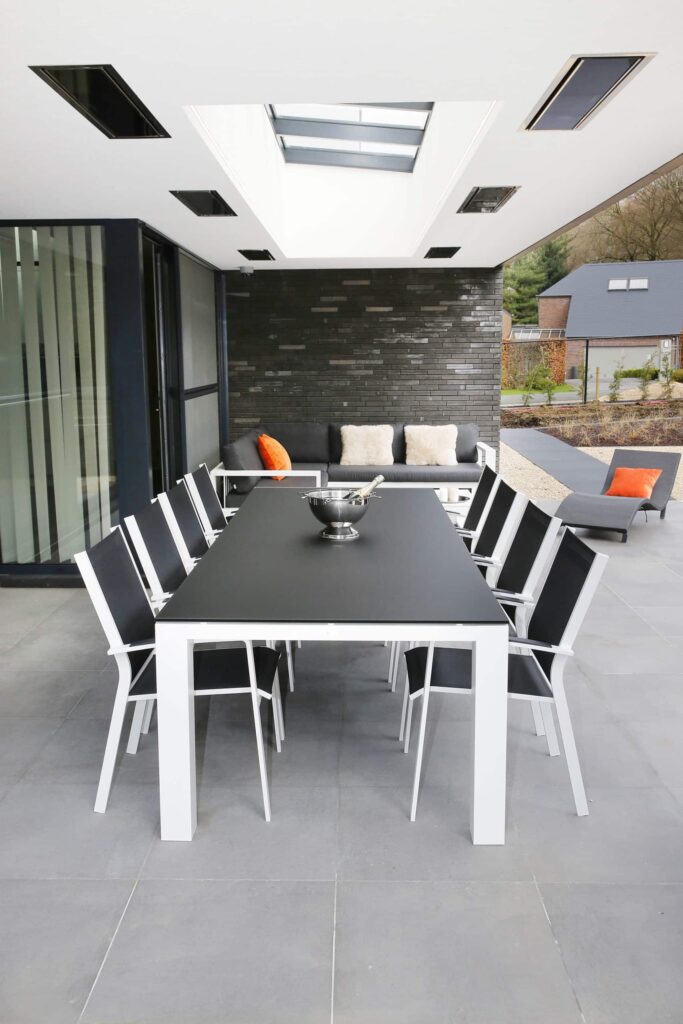 Table noire huit places dans un espace extérieur en plein air avec toit ouvrant et chauffage par le toit.