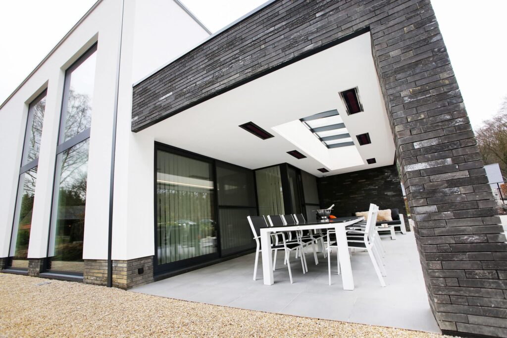 Espace extérieur moderne gris et blanc avec briques noires, toit ouvrant et chauffages électriques.